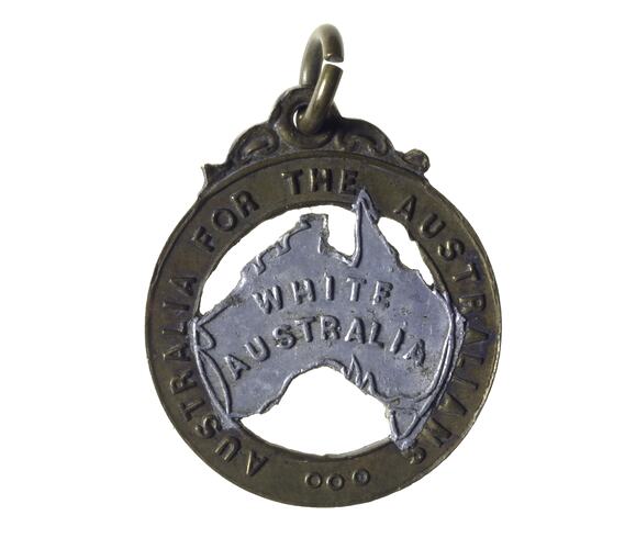 Medal with silver coloured Australia map in open cut brass band border. Raised lettering on map and border. Scroll and loop at top.