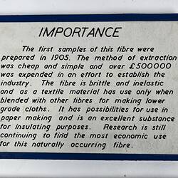 White rectangular exhibtion label with black text and blue border.