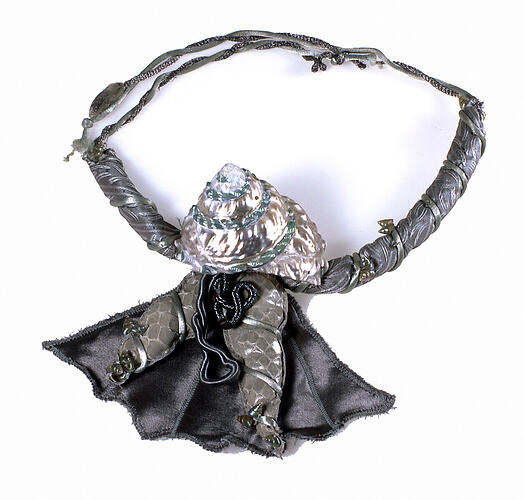 Decorative fabric necklace with a large pearly shell.
