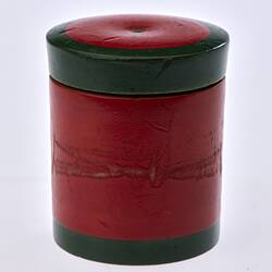 Red painted, cylindrical wooden box. Dark green trim around lid and base.