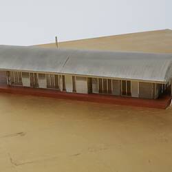 Model of a house with an arched roof, corrugated iron and wide expanses of glass.