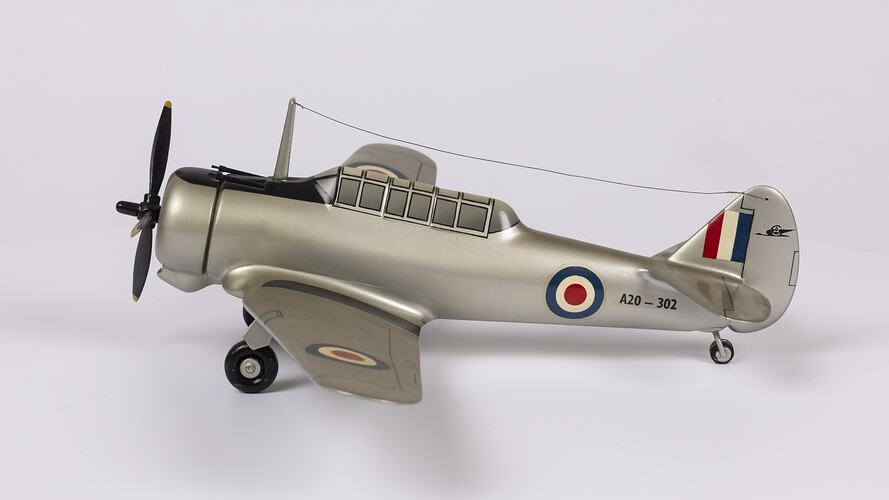 Silver model aeroplane. Red, white, blue roundels on wings and body. Flag on tail. Black propeller and wheels.