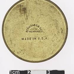 Round gold coloured medal with text in centre.