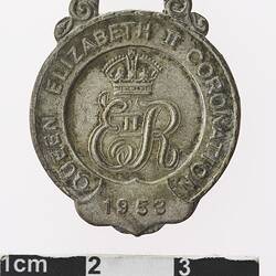 Silver coloured medal with crown and initial E and R, and text surrounding.