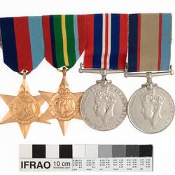 Group of four medals mounted in a row, with multicoloured ribbons attached to top of medals.