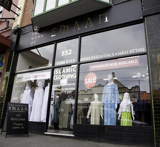 Black shopfront with large windows. Women's and children's clothing displayed on mannequins.