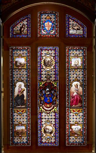Stained glass window. Three longer vertical panels, each with a smaller section above.