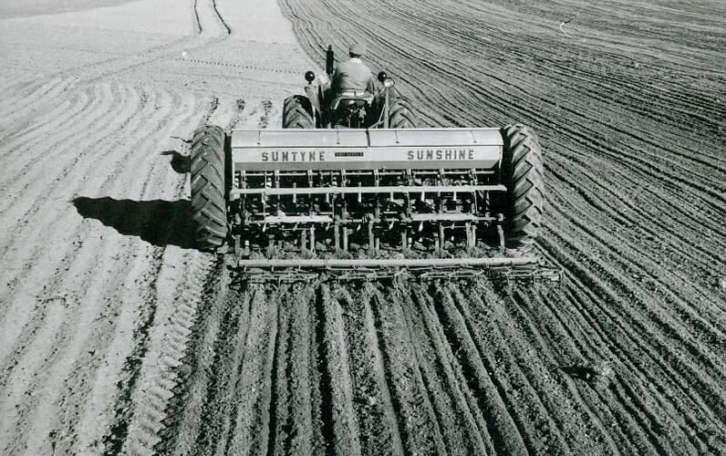 Rear of seed drill and tractor sowing crop.