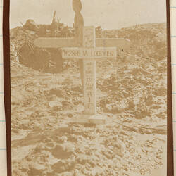 Two crosses covered in writing with barren landscape behind.