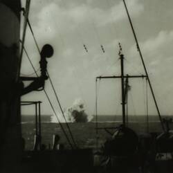View of underwater explosion seen from deck of a military battleship.