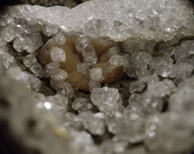 Peach-coloured mineral almost enclosed within clear crystals.
