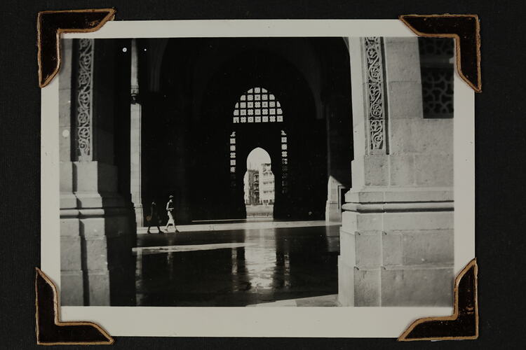 View of interior of a monument, two people in distance walking through an archway.