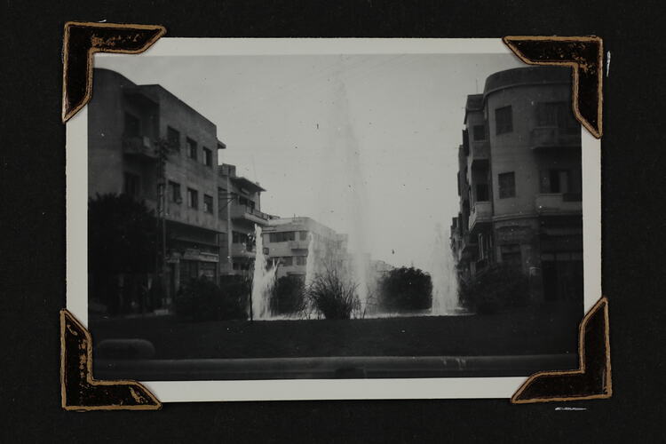 Water fountain in centre with buildings on either side.