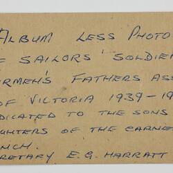 Paper tag on thick brown card stock, with blue handwritten text.