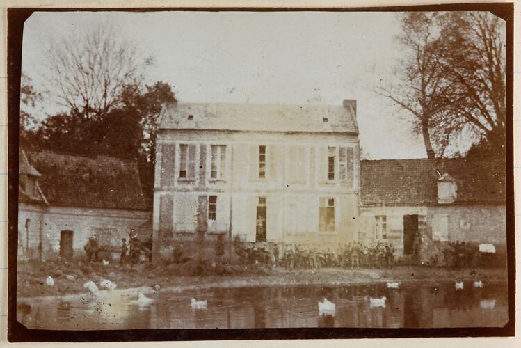 Two storey farm house with a lake in front.