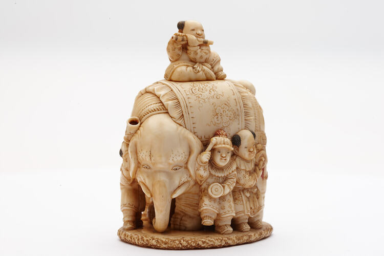 Ornately carved ivory elephant with musicians around it and one sitting atop.