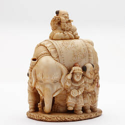 Ornately carved ivory elephant with musicians around it and one sitting atop.