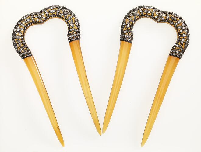 Pair of hairpins with decorative bejewelled arch and cream coloured pointed arms.
