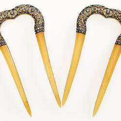 Pair of hairpins with decorative bejewelled arch and cream coloured pointed arms.