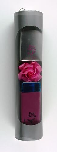 Grey cylindrical package with clear window. Contains pink and silver cosmetic items.