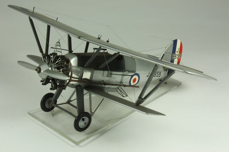 Silver model biplane model with red, white, blue rondels on wings and fuselage. Silver propeller.