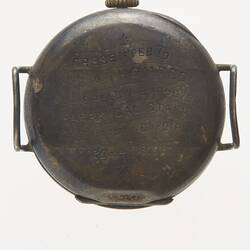 Back of metal watch with engraved inscription. Hinged case. No wrist strap but has metal lugs.