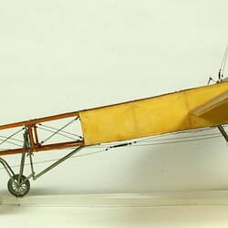 Model aeroplane with exposed wooden frame and off white panelling. Side view.