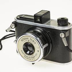 Black camera with metal trim. Wrist strap. Front angle view.