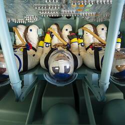 Top view looking down at three seated astrounauts with control panel in front of them.