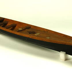 Wooden boat with black hull, three quarter view.