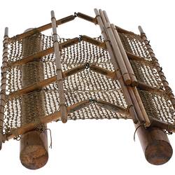 Raft model made of wood and twine. Two cylindrical floats are attached to framework. Net platform.