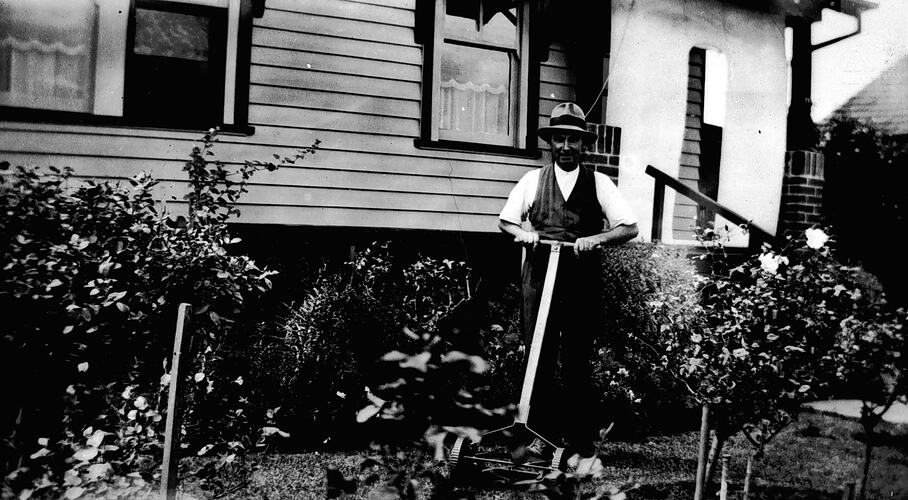 [Ern Phillips mowing the lawn, Beaver Street, Essendon, about 1940.]