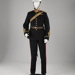 Navy officer's uniform with gold at cuff, epaulettes, belt. Brass buttons. Red/gold collar. White helmet.