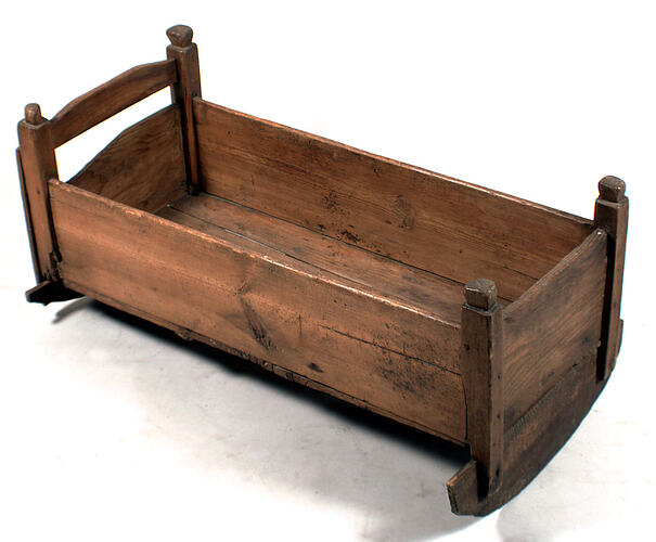 Wooden cradle with curved base for rocking.