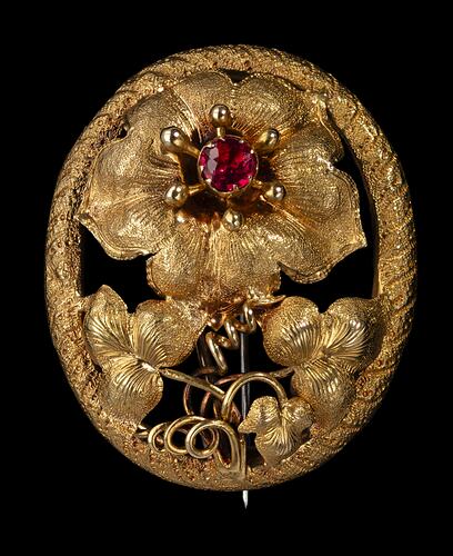 Gold brooch with large flower with red centre, supported by two lower leaves and tendrils, inside an oval border.
