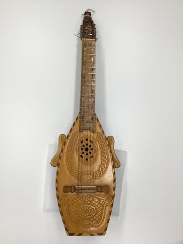 Brown wooden mandolin. Carved patterns on body. Silver pegs.