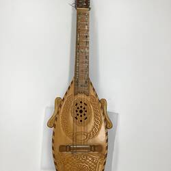 Brown wooden mandolin. Carved patterns on body. Silver pegs.
