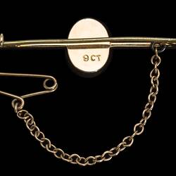 Back of gold bar brooch with central oval opal. Fine saftey chain attached at left.