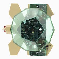 Plastic computerised turtle toy. Clear green body shell above fawn base with two red light 'eyes'. Top view.