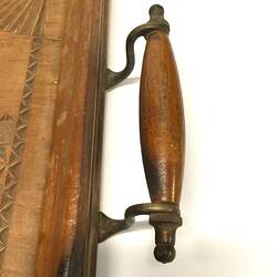 Wood and metal handle detail on carved wooden tray.