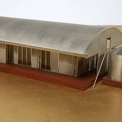 Model of a house with an arched roof, corrugated iron and wide expanses of glass.