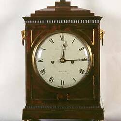 Brown wooden clock set to 15 minutes past 12.