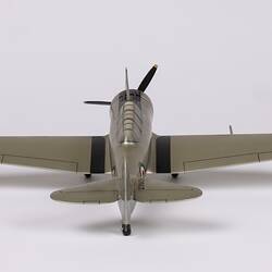 Back view of silver model aeroplane. Red, white, blue roundels on wings and body. Black propeller and wheels.