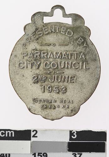 Silver coloured medal with text.
