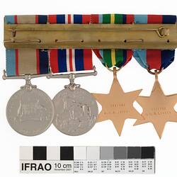 Group of four medals mounted on a bar, with multicoloured ribbons attached to top of medals.