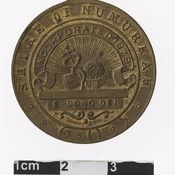 Round bronze coloured medal with coat of arms and text surrounding.
