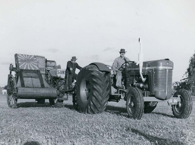 A tractor towing an early model stripper harvester.
