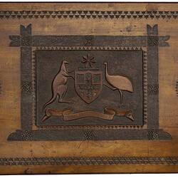 Carved wooden table top with Australian arms, decorative motifs and border.