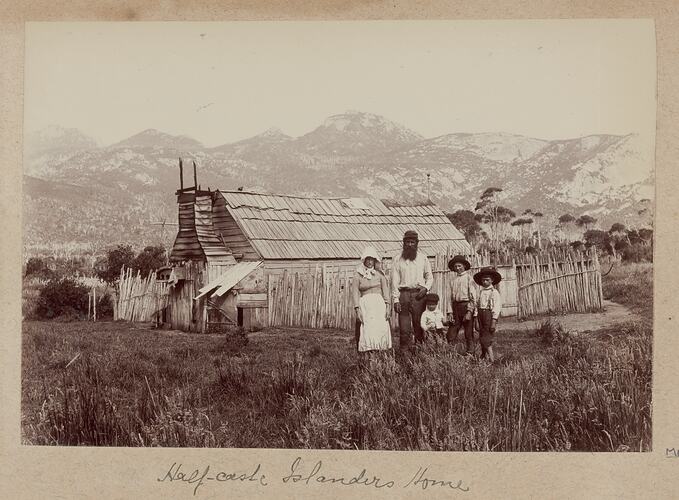 Family in front of their timber home in a bush setting.