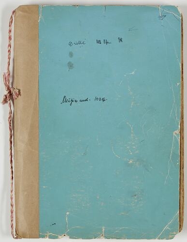 Worn pale blue notbook with handwritten text on front. String along spine.